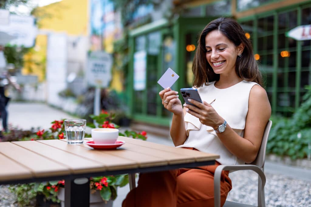 Kvinna sitter med kreditkort i handen på cafe - Ekomni - Kredittjänster och snabblån