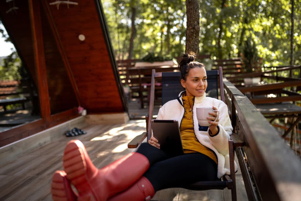 Kvinna tittar på utsikt med surfplatta i sin hand - Ekomni - Kredittjänster och snabblån - Låna pengar utan uc